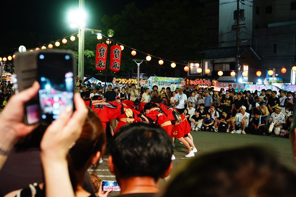 夜の交差点で円陣を組む寶船